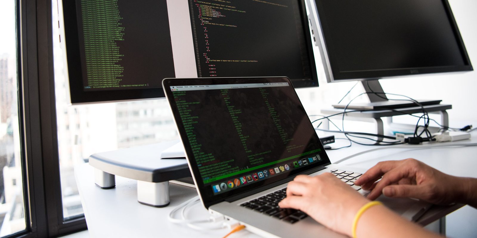 Someone typing on a Mac, database commands on-scree, monitor with code | Apple's privacy focus means less personalized apps, fewer features