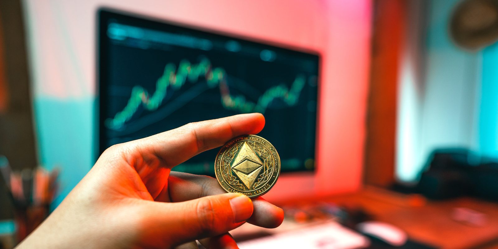 Ethereum coin held up in front of iMac with crypto graph | iCloud crypto wallet attack saw $650k stolen from trader within seconds