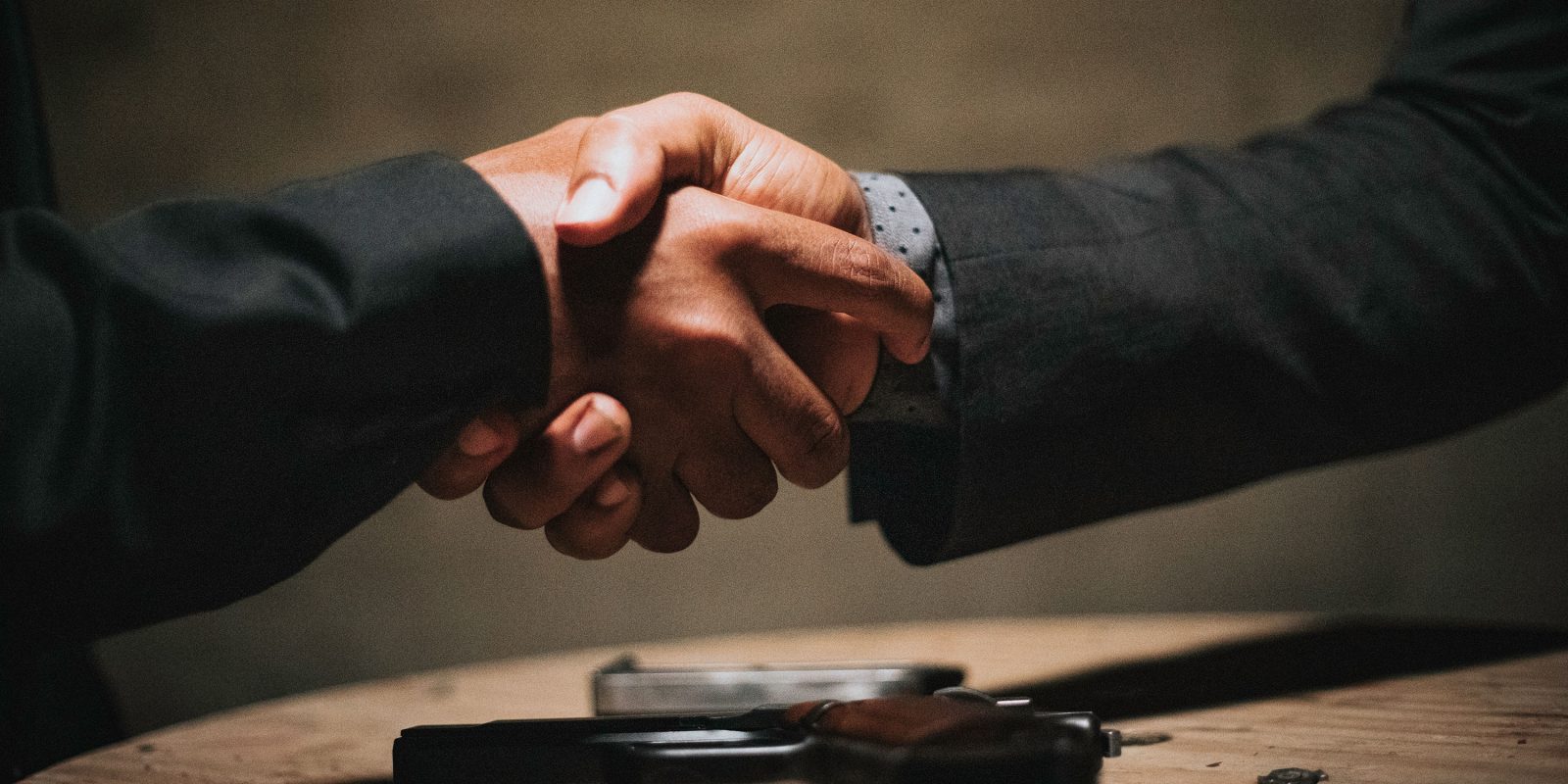Photo shows two men in suits shakings hands | Apple's antitrust mess could so easily be ended, at likely minimal cost