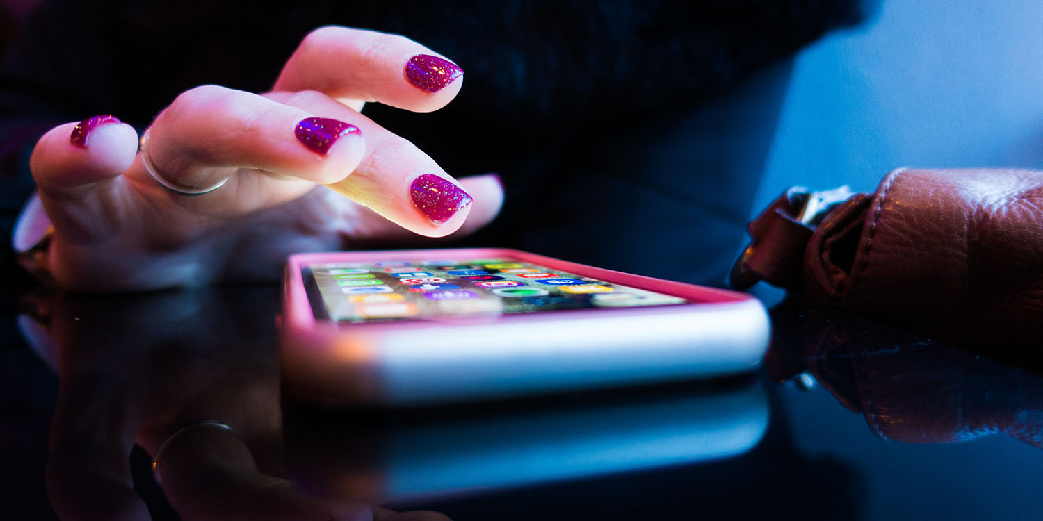 Top of the App Store | Woman's finger poised over iPhone home screen