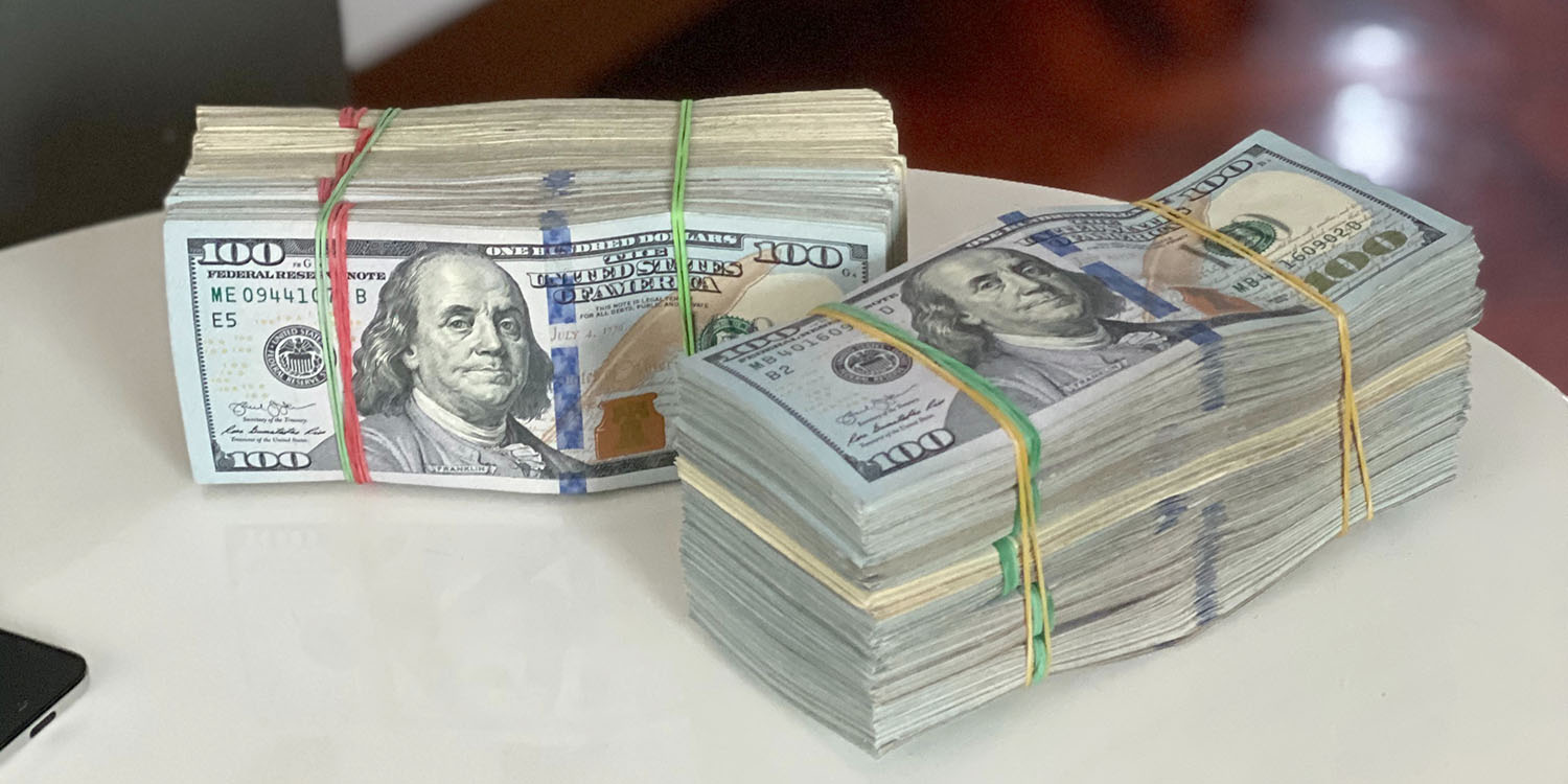 Tech lobbying spend | Large bundles of $100 bills on a table