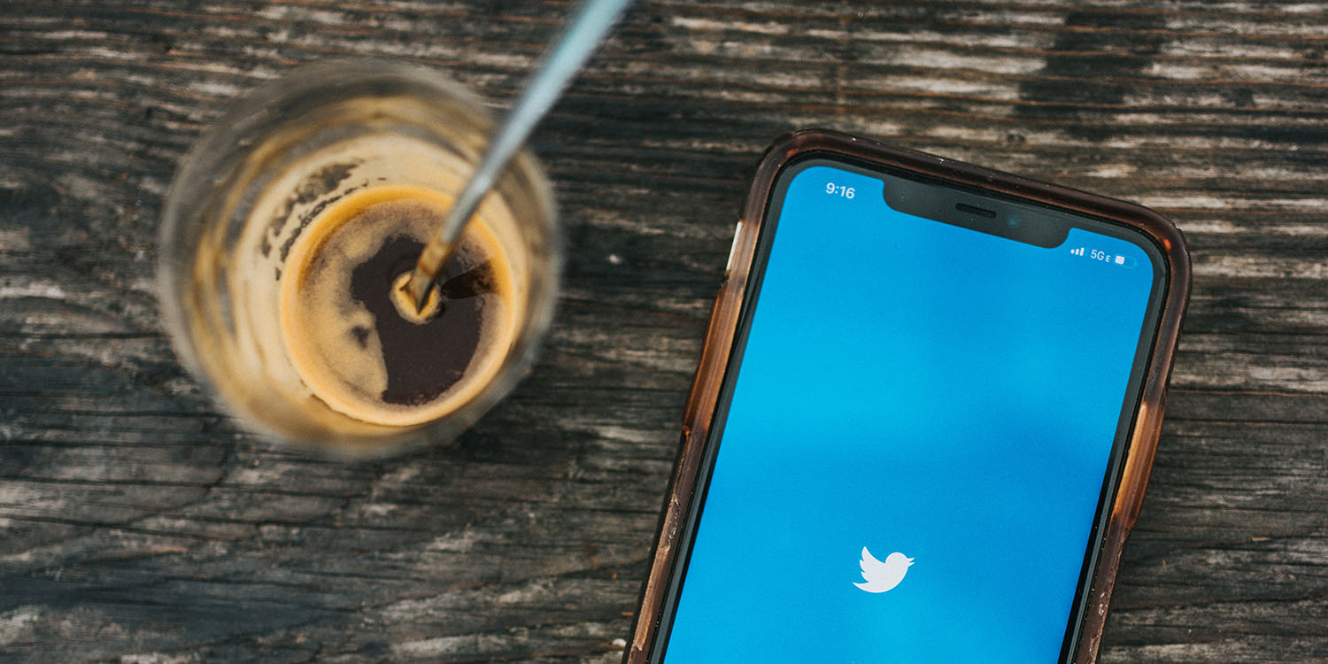Twitter status feature | iPhone on desk with Twitter open, next to espresso cup