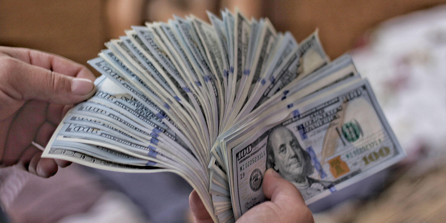 TikTok election fundraising banned | Hands counting $100 bills