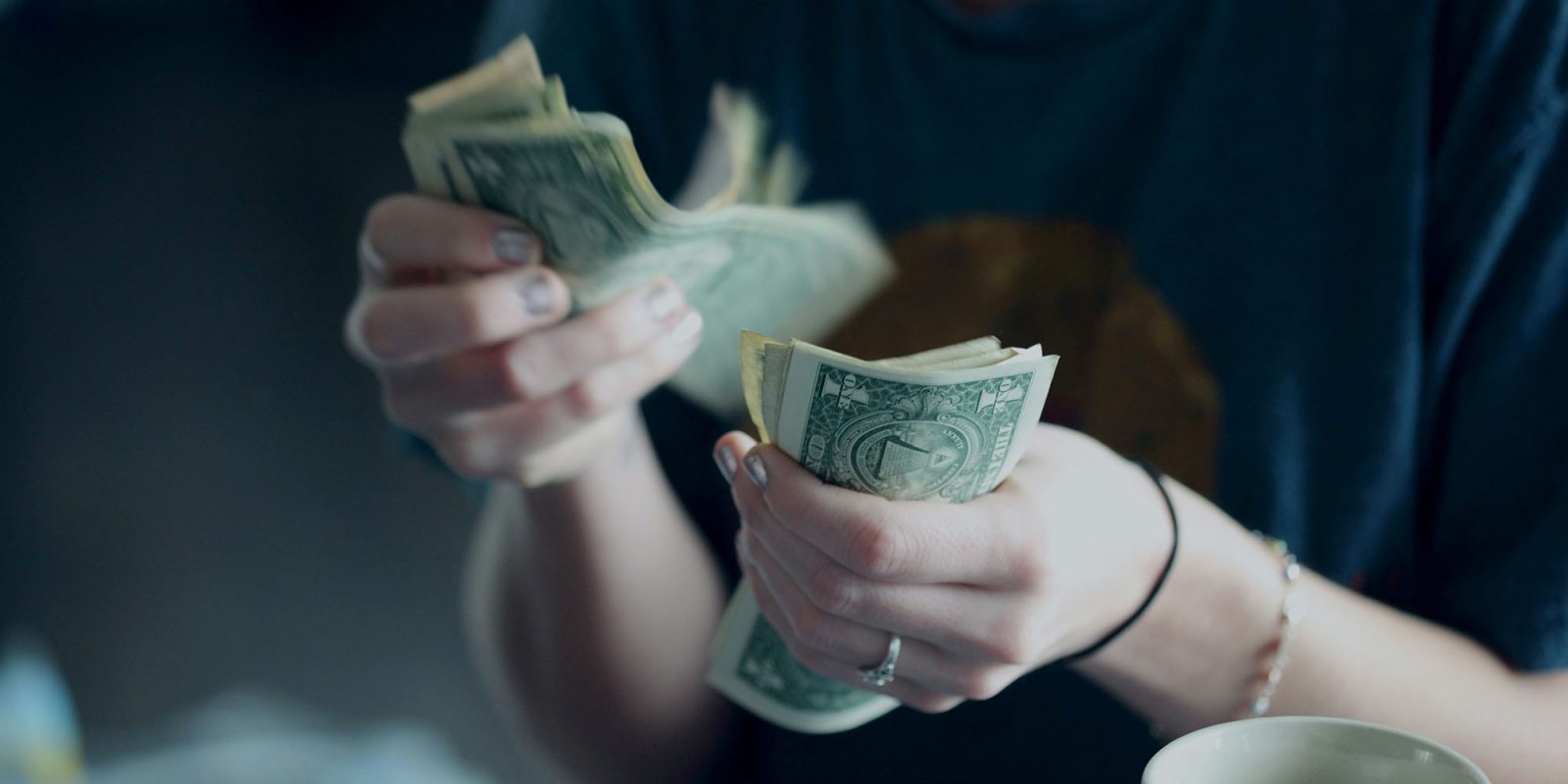 Tim Cook was overpaid claim | Woman's hands, counting out dollar bills