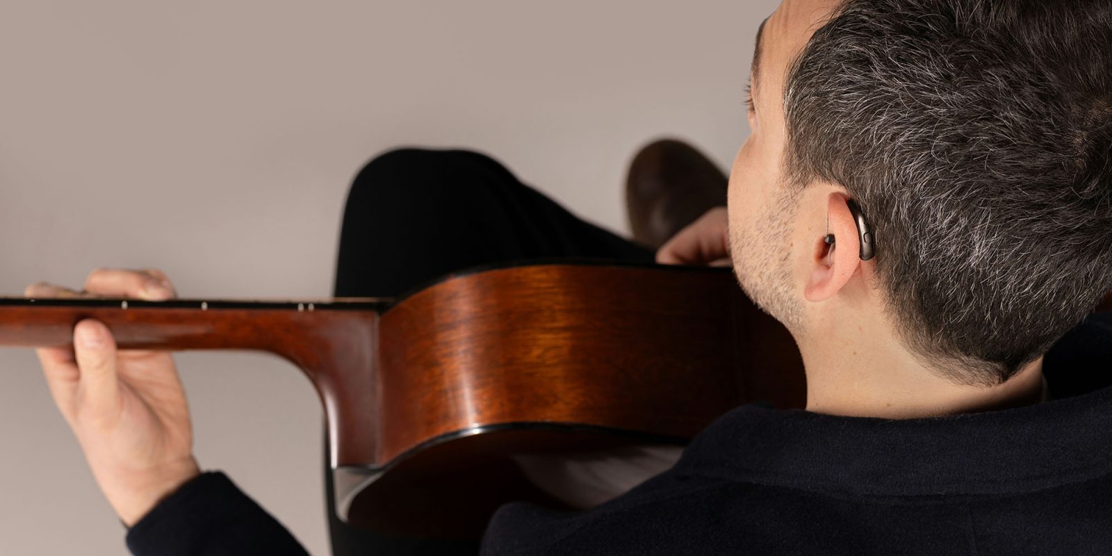 All smartphones will have to be compatible with all Bluetooth hearing aids | Man wearing a GN hearing aid while playing guitar