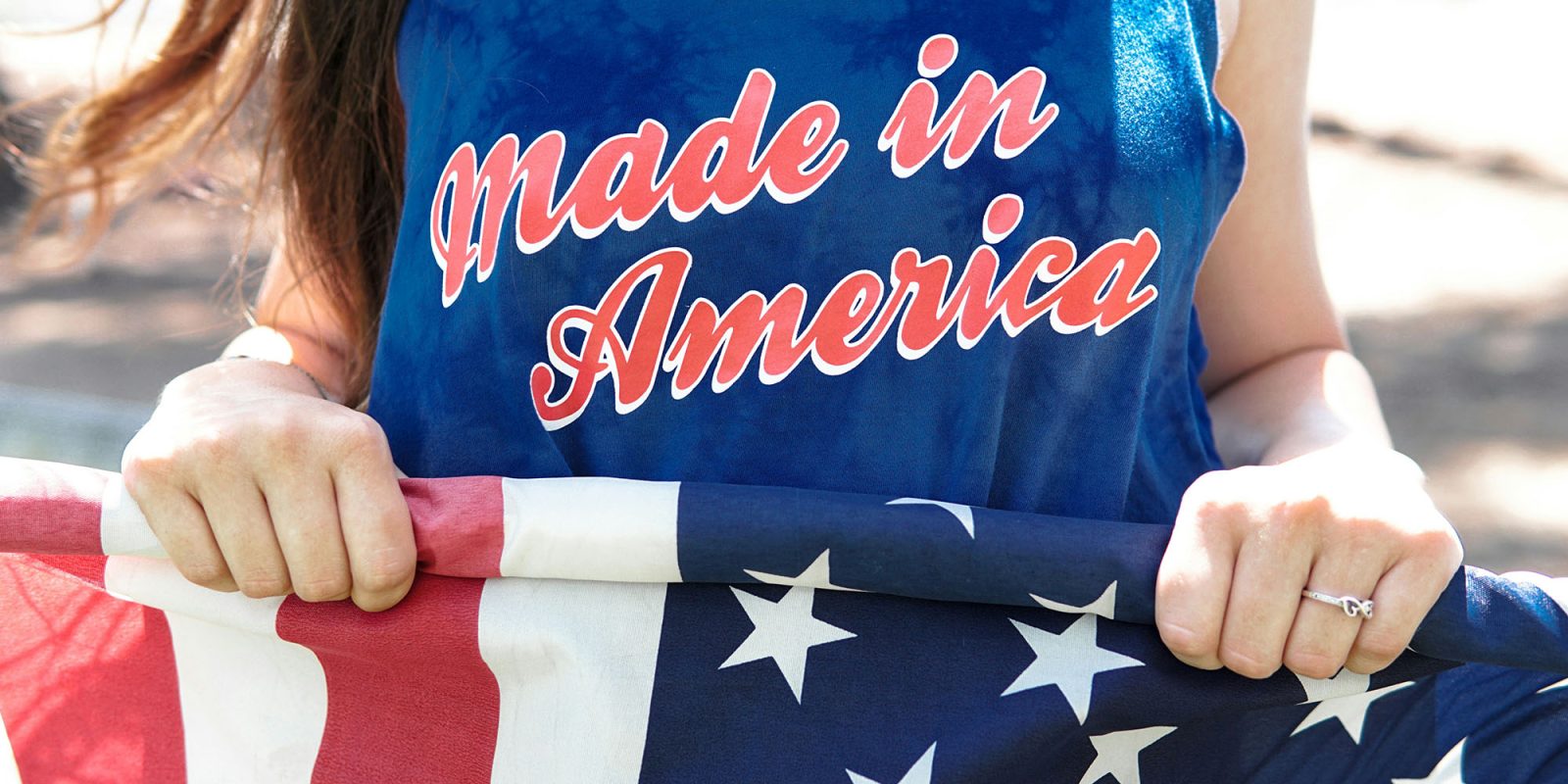 The 2,700 reasons a made-in-USA iPhone would be a non-starter | Woman wearing a Made in America t-shirt and carrying a US flag