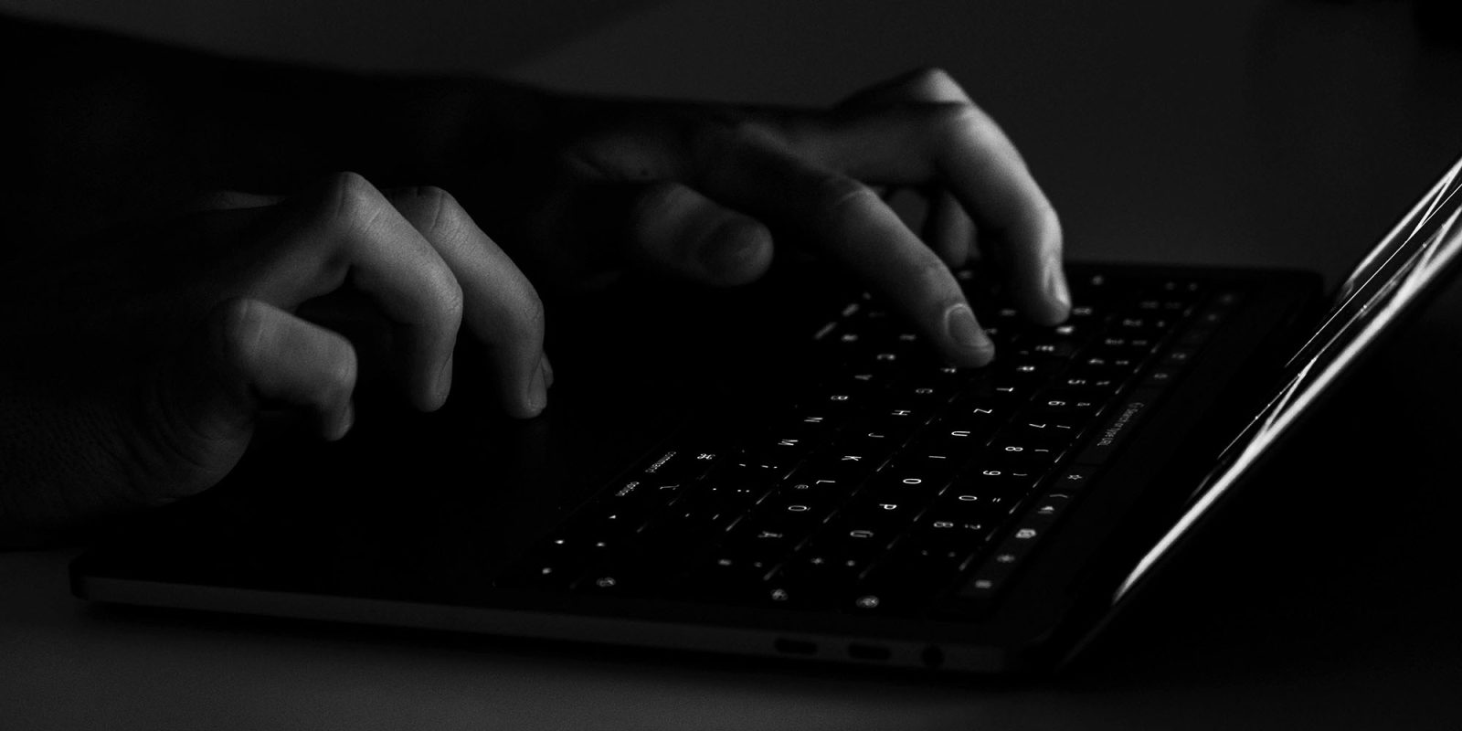 Apple warns iPhone users in 100 countries that they are victims of spyware | Creepy-looking low-key b&w photo of hands typing on a keyboard