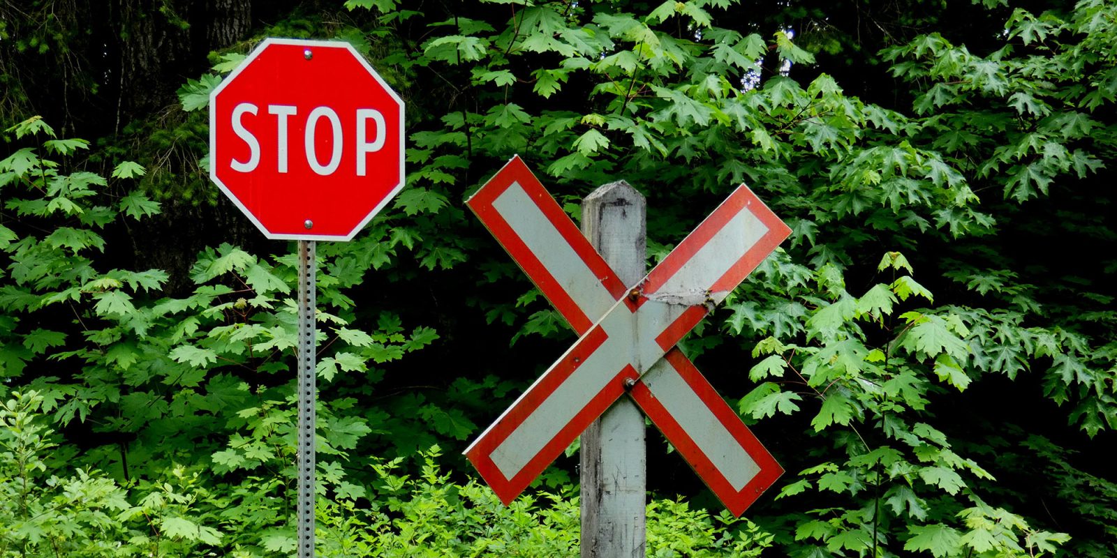 370k Grok AI chats made public without user consent | Stop sign next to an X sign at a railroad crossing