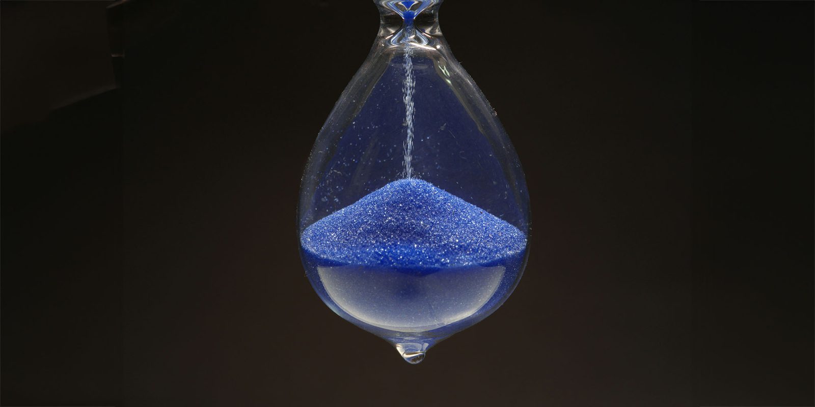 Apple says EU law will mean more features are delayed, maybe even new hardware | Close-up photo of hourglass with blue sand