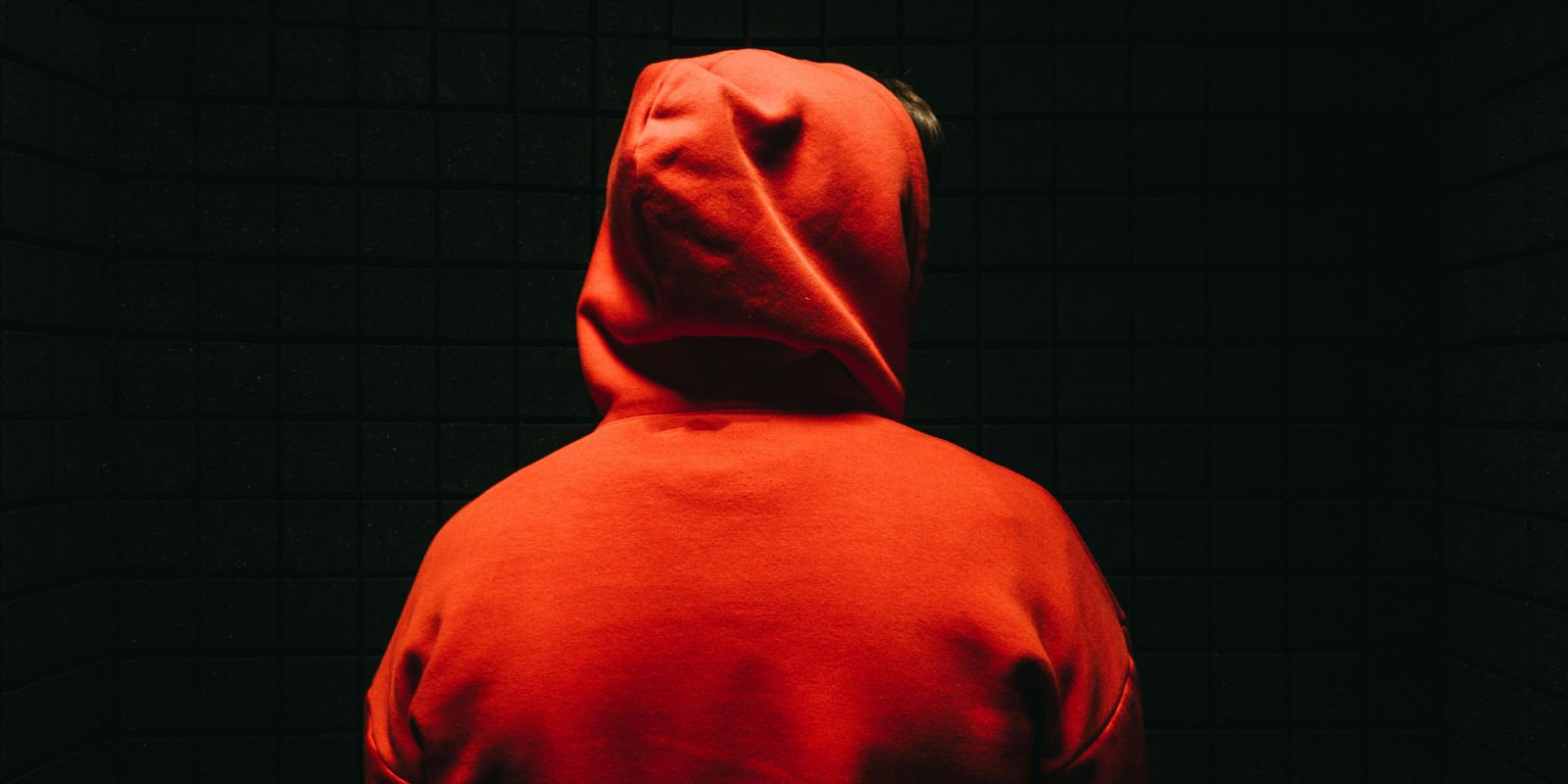 Apple under legal scrutiny in the EU over scam apps | Face hidden by hoodie and darkness