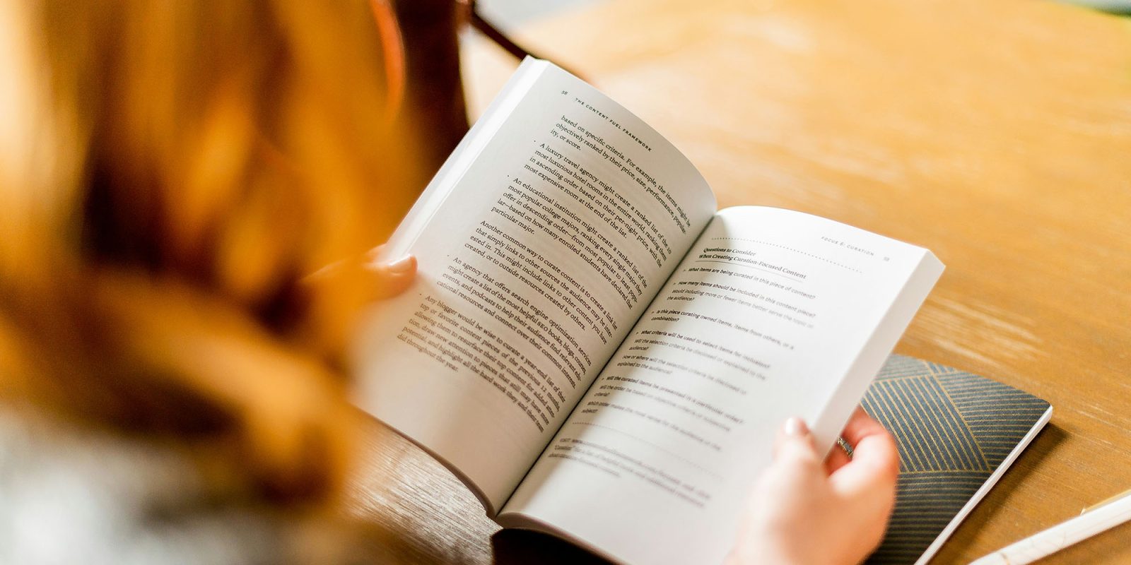 Spotify's Page Match may sync audiobooks with paper versions | Photo shows a close-up of a woman reading a book in a cafe